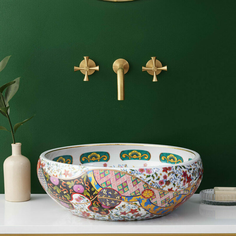 Yasmin basin against deep green wall pictured with Theo tap in brushed brass and Hugo single vanity unit