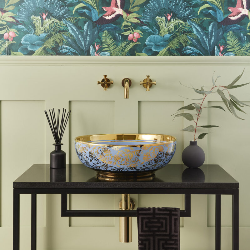 Carmel countertop basin with Theo tap in polished brass and Hugo vanity unit against in bathroom with maximalist wallpaper