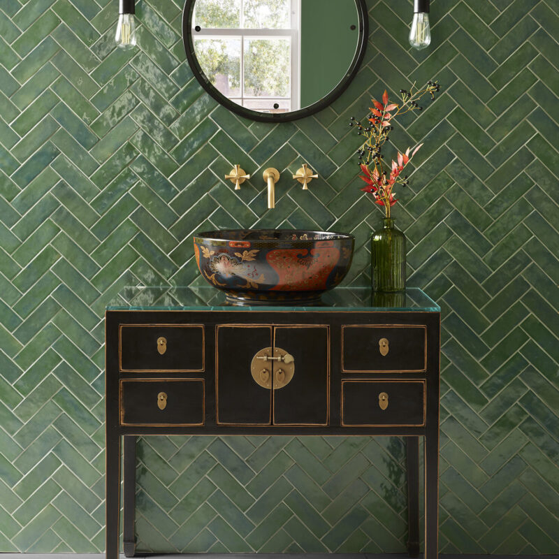 Huxley single vanity unit against a tiled green wall with Ophelia basin, Theo tap in brushed brass and Otto mirror in black