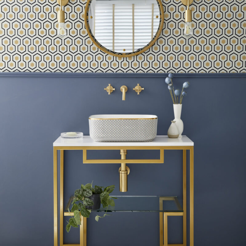 Luxury countertop bathroom basin with art deco pattern on a freestanding vanity unit against blue painted walls.