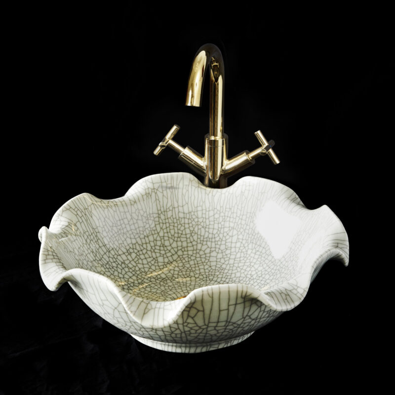 Celestine basin in green-blue colour against a black background with polished gold Arlo Tap.